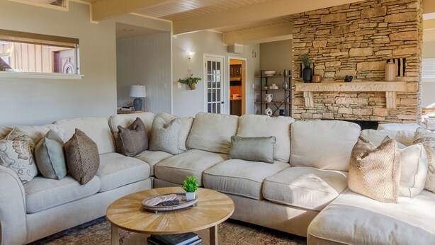 Ein Wohnzimmer mit einem Ecksofa, einem Couchtisch und einem Kamin aus Stein.