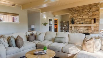 A living room with a sectional sofa, a coffee table, and a stone fireplace.