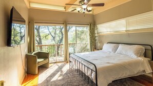 Ein Schlafzimmer mit einem Bett, einem Sessel, einem Deckenventilator und großen Fenstern.