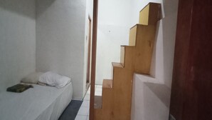 A bedroom with a bed, a wooden staircase, and a door leading to another room. - SPOT ON 93964 Guest House Pak Gatot 3 (Bandung)