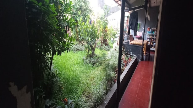 A view from a window overlooking a garden with various plants and a red tiled floor inside a building. - SPOT ON 93964 Guest House Pak Gatot 3 (Bandung)
