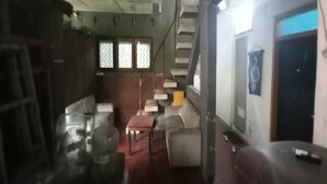 A room with a staircase, a sofa, a table, and a chair. - SPOT ON 93964 Guest House Pak Gatot 3 (Bandung)