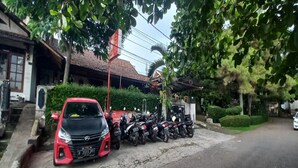 A red car parked on a street with a row of motorcycles lined up on the side. - SPOT ON 93964 Guest House Pak Gatot 3 (Bandung)