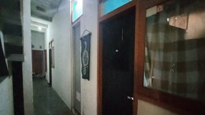 A narrow hallway with a closed door on the right, a wall-mounted decoration, and a tiled floor. - SPOT ON 93964 Guest House Pak Gatot 3 (Bandung)