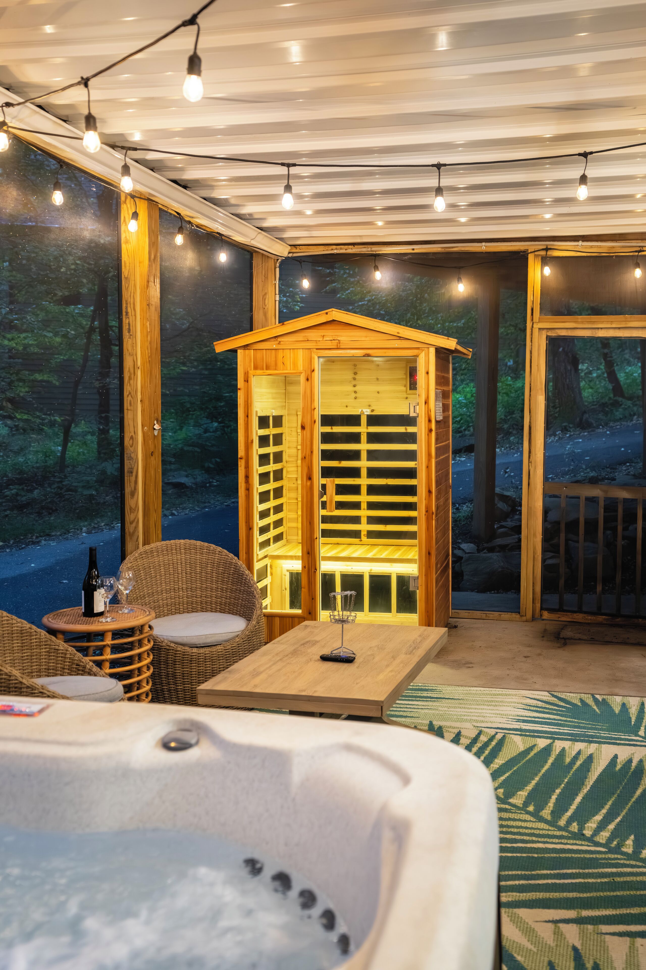 A cozy cabin with a hot tub, wicker furniture, and a wooden sauna.