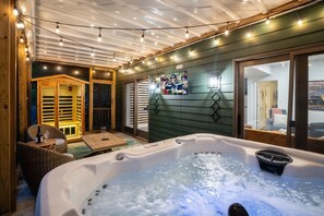 Ein Bereich mit Whirlpool, Holzboden, Lichterkette und einem Fernsehbildschirm.
