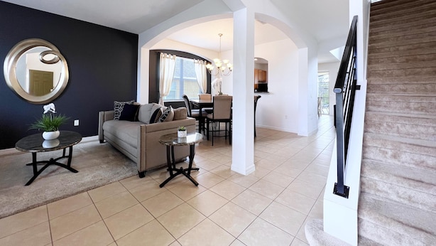 A modern living room with a sofa, coffee table, and a dining area with chairs and a table. - Gorgeous 6Bd Pool Hm Providence-2256CA (Davenport)