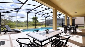 A covered outdoor area with a pool, lounge chairs, and a table with chairs. - Gorgeous 6Bd Pool Hm Providence-2256CA (Davenport)