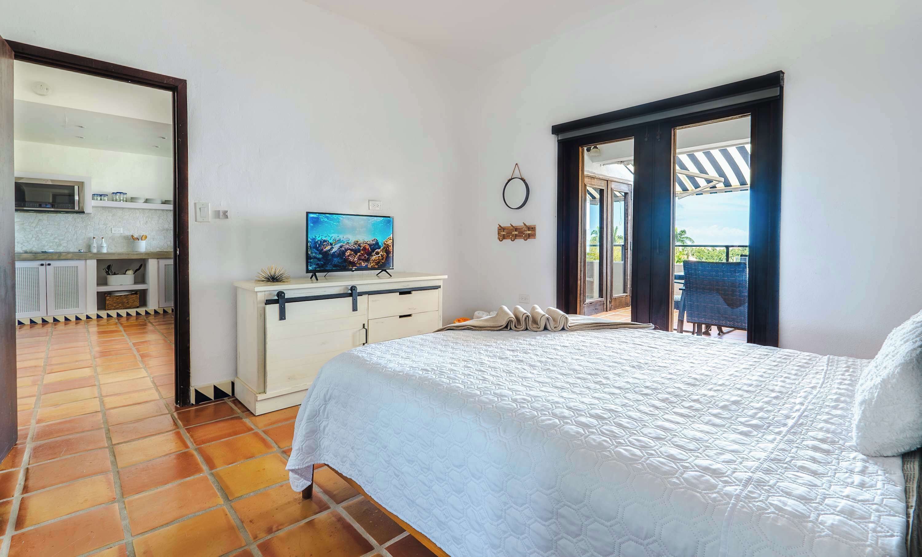 Une chambre avec un lit, une télévision, un coin cuisine et un balcon.