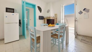 A kitchen with a white refrigerator, a dining table with chairs, a microwave, and a window with a view.