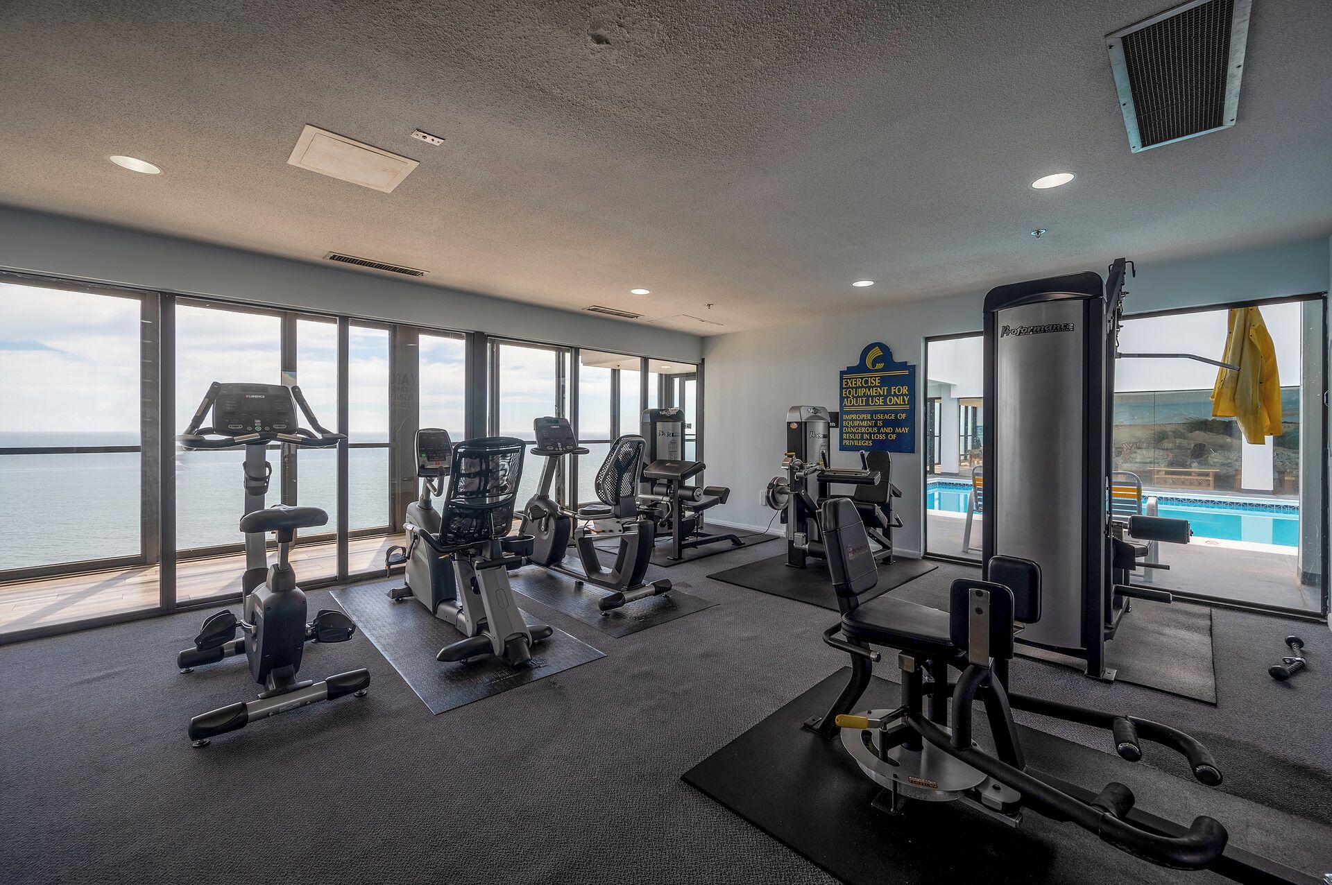 A gym with cardio machines, weight stations, and a view of the ocean.