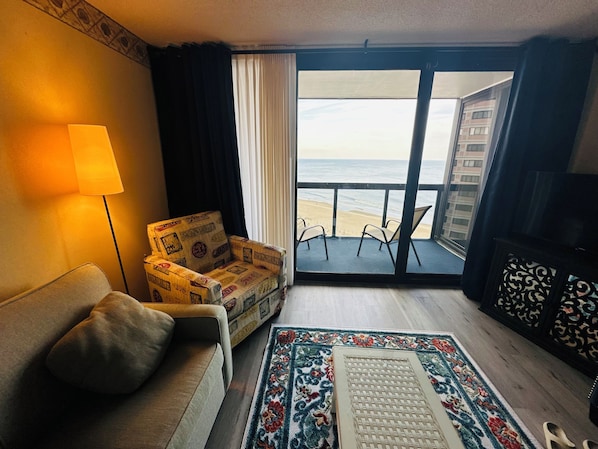 A room with a sofa, a patterned armchair, a small table, a decorative rug, and a view of the beach through a glass door. - “Ocean Pearl”
Luxury oceanfront with two pools. (Ocean City)