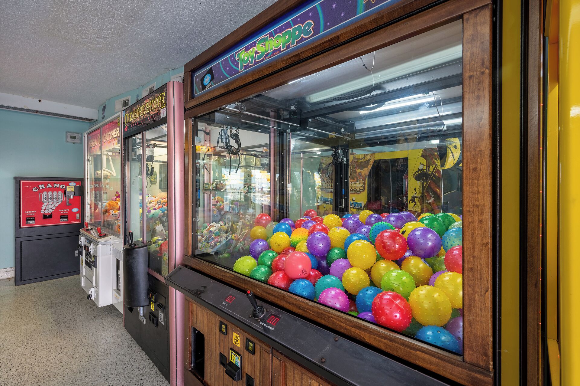A claw machine filled with colorful balls, a 'ToyShoppe' sign, and a 'Change' coin dispenser.