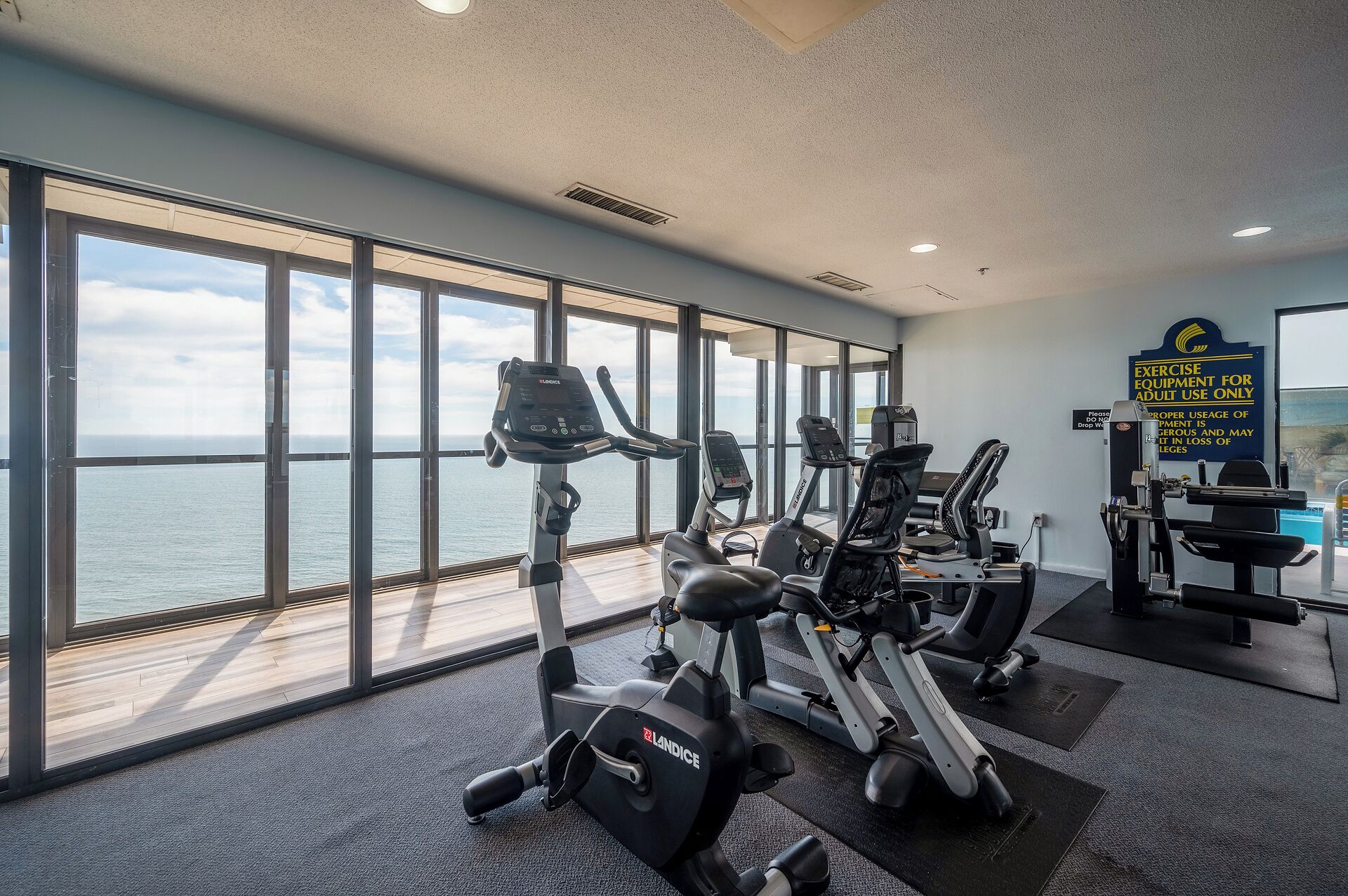 Un gimnasio con máquinas de cardio y vista al mar.