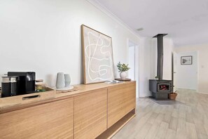 A modern living room with a wooden console table, a large abstract painting, a fireplace, and a view into another room. - Luna Getaway—Spacious Family Escape by the Coast (Quindalup)