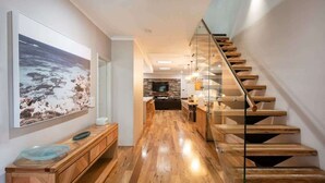 A modern kitchen with a wooden countertop, a large framed picture, and a staircase with wooden steps. - The Bay Retreat (Dunsborough)