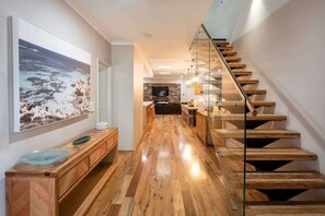 A modern kitchen with a wooden countertop, a large framed picture, and a staircase with wooden steps. - The Bay Retreat (Dunsborough)
