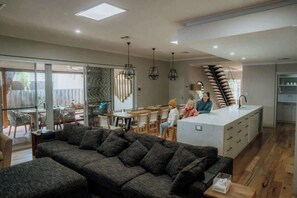 A modern living room with a sofa, dining area, and kitchen. - The Bay Retreat (Dunsborough)