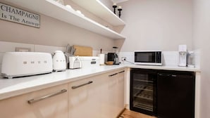 Eine Küche mit weißen Schränken, einem schwarzen Geschirrspüler, einer Mikrowelle, einer Kaffeemaschine und einem Toaster.