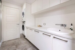 A modern bathroom with a white sink, a mirror, and a towel rack.