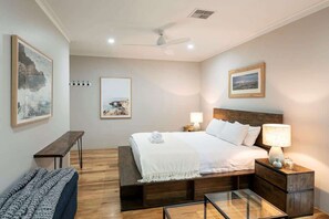 A hotel room with a bed, bedside tables, a bench, and artwork on the walls.