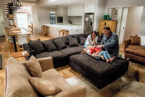 A modern living room with a sectional sofa, a dining area, and a kitchen in the background. - The Bay Retreat (Dunsborough)