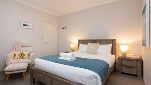 A bedroom with a bed, a chair, a nightstand, and a door. - The Bay Retreat (Dunsborough)