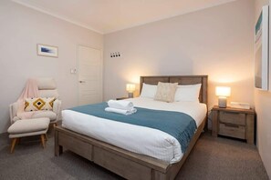 A bedroom with a bed, a chair, a nightstand, and a door. - The Bay Retreat (Dunsborough)
