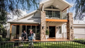 Ein zweistöckiges Haus mit einer Veranda, Steinpfeilern und einer Garage.