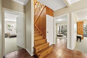 A staircase with wooden steps and a wooden railing, leading to a room with a bed and a window.