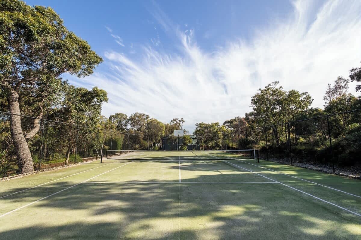 Un campo da tennis all'aperto circondato da alberi.