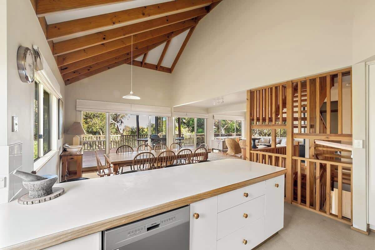 A spacious kitchen with a large island, wooden beams, and a view to an outdoor patio.