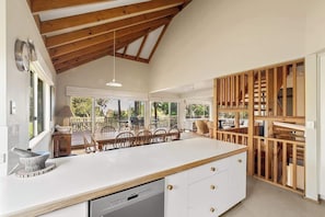 A spacious kitchen with a large island, wooden beams, and a view to an outdoor patio.
