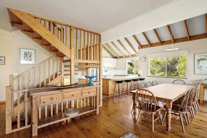 Eine geräumige Küche mit Holzboden, ein Essbereich mit großem Tisch und Stühlen sowie eine Holztreppe.