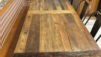 A dining table with a rustic wooden finish, surrounded by metal chairs.