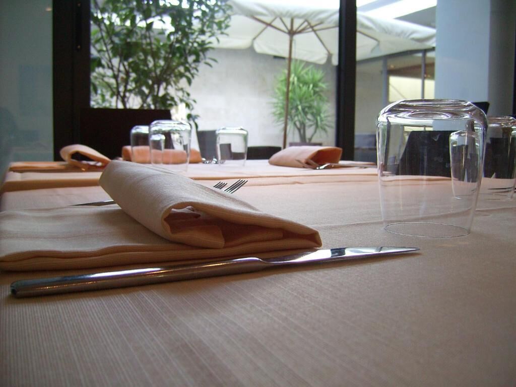 A table set with a folded napkin, a fork, and a glass.