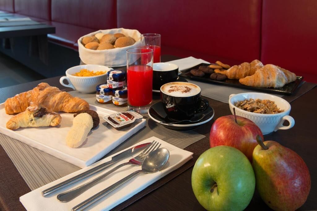 A breakfast setting with croissants, apples, a coffee cup, and a bowl of cereal.