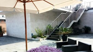 Un espace extérieur aménagé en patio, avec un escalier, des sièges et des plantes en pot.