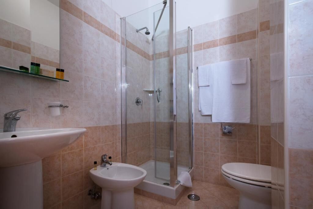 A bathroom with a glass-enclosed shower, a sink, and a toilet.