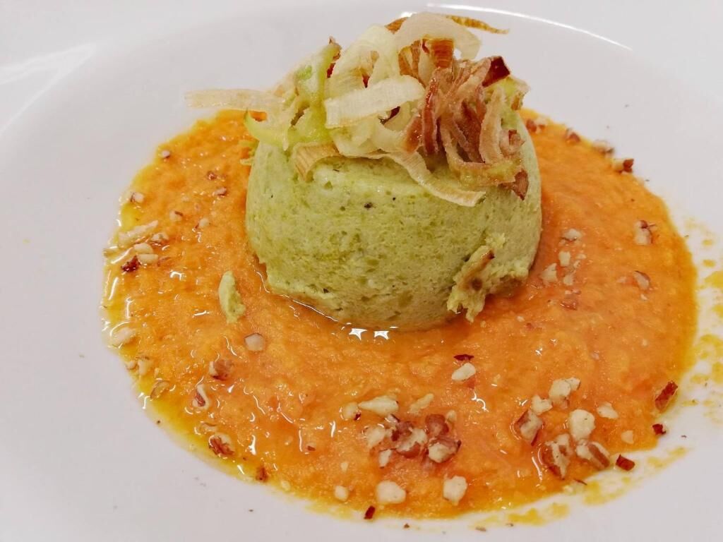 A dessert with a green mound and orange sauce on a white plate.