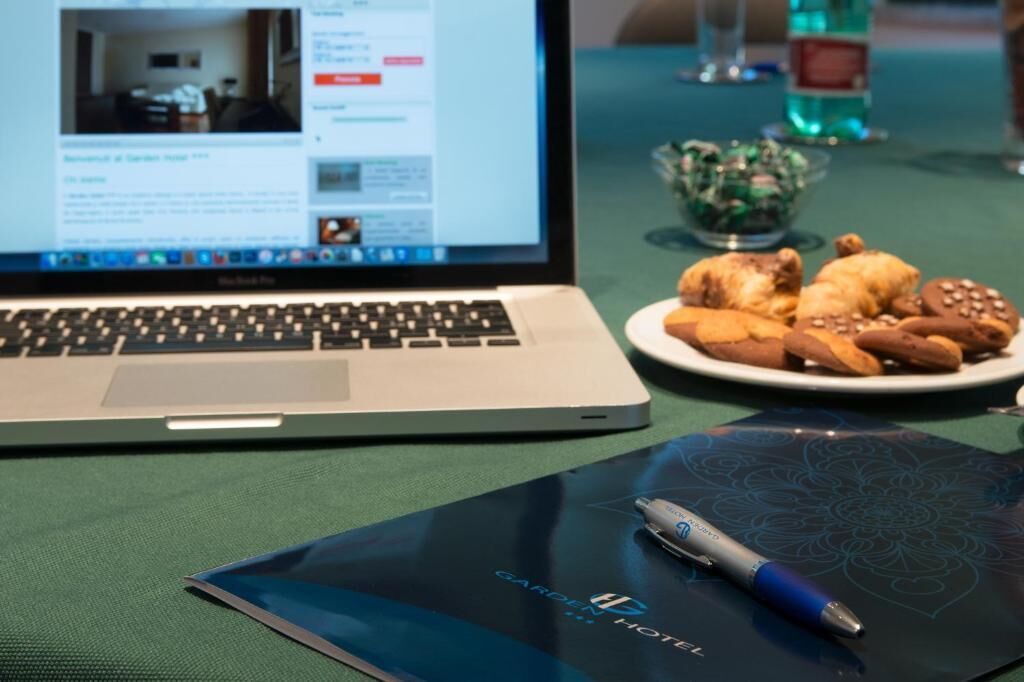 A laptop on a table with a plate of cookies and a pen.