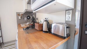 Una kitchenette compacta con tostadora, hervidor y distintos utensilios.