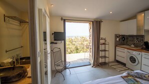Una habitación de hotel compacta con balcón, lavadora y televisión.