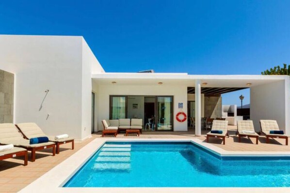 A modern pool area with lounge chairs and a clear blue pool.