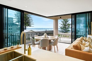 Ein moderner Essbereich mit Meerblick, ein Balkon mit Geländer und eine Couch mit Kissen.