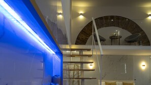 Un dormitorio moderno con una cama, una escalera y una pared iluminada en azul.