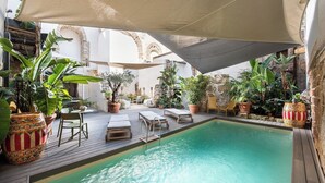 Un área de piscina con sillones de descanso y plantas en macetas.