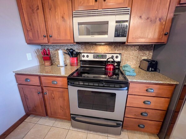 Una cocina con armarios de madera, una estufa de acero inoxidable, un microondas y un tostador.