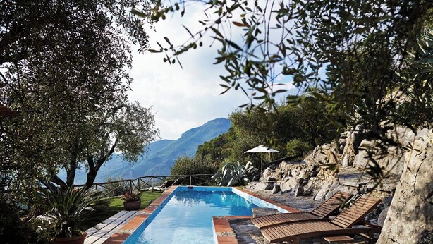 Un espace piscine avec des chaises longues et une vue sur les montagnes.