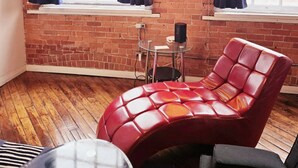 A furnished room with a red leather chair, a small table, and a neon sign on the wall. - Spacious Loft w/ Riverfront Views & Comfort! (Detroit)